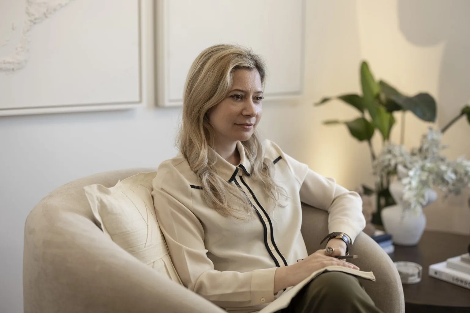 A psychotherapist sitting in a calm, softly lit consulting room at London Bridge Therapy, holding an open notebook during a session.