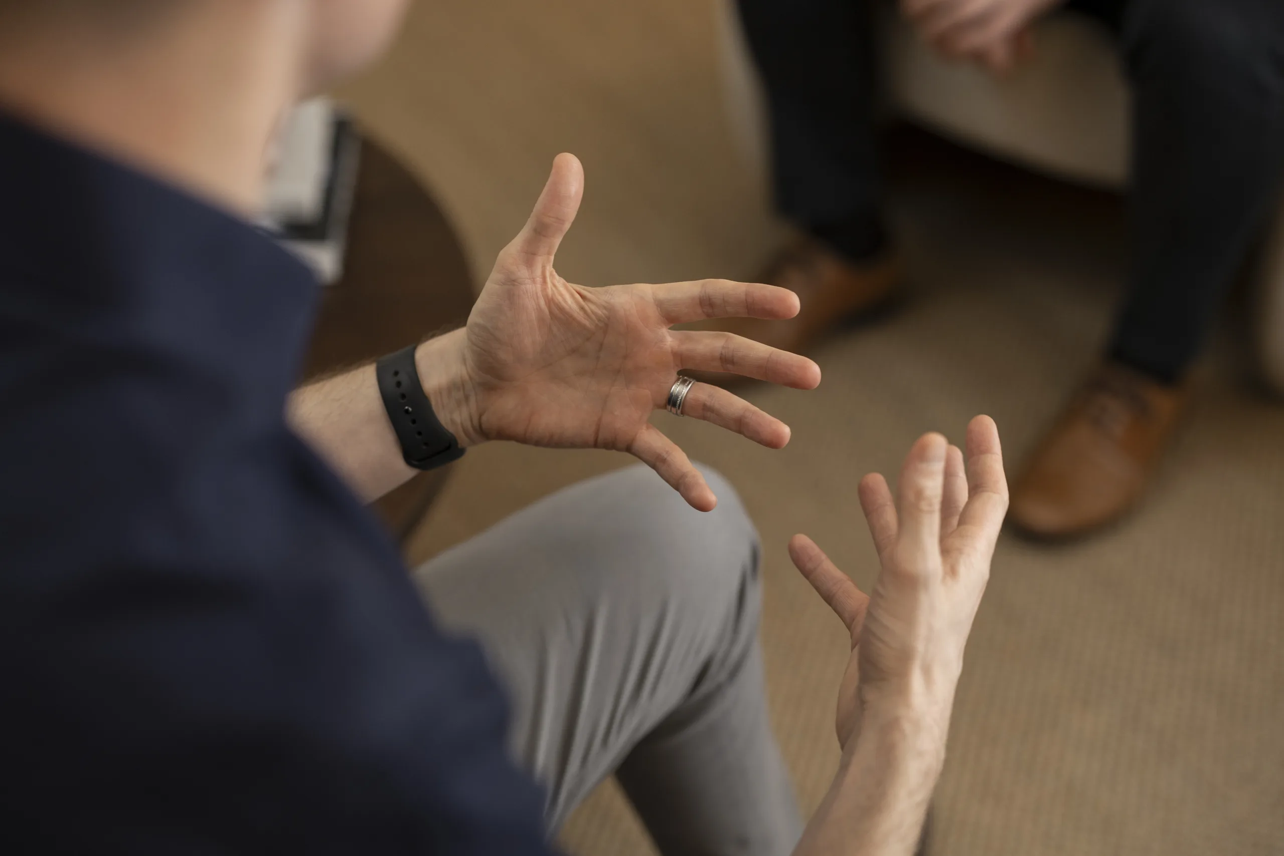 Two people in a therapy session, with open hand gestures suggesting active conversation and engagement
