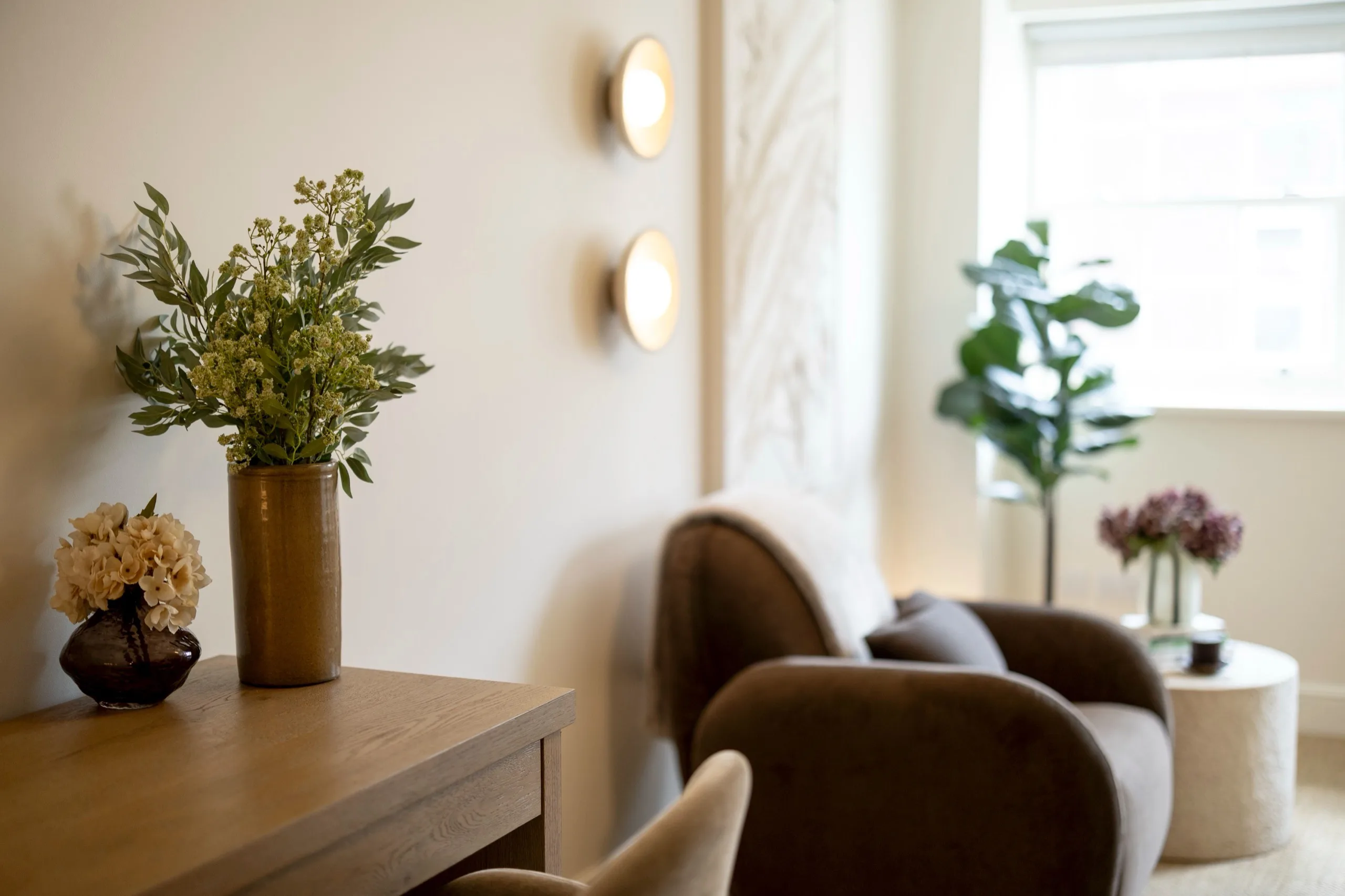 Therapy Room at London Bridge Therapy with two armchairs, soft wall lighting and fresh flowers on a wooden console table