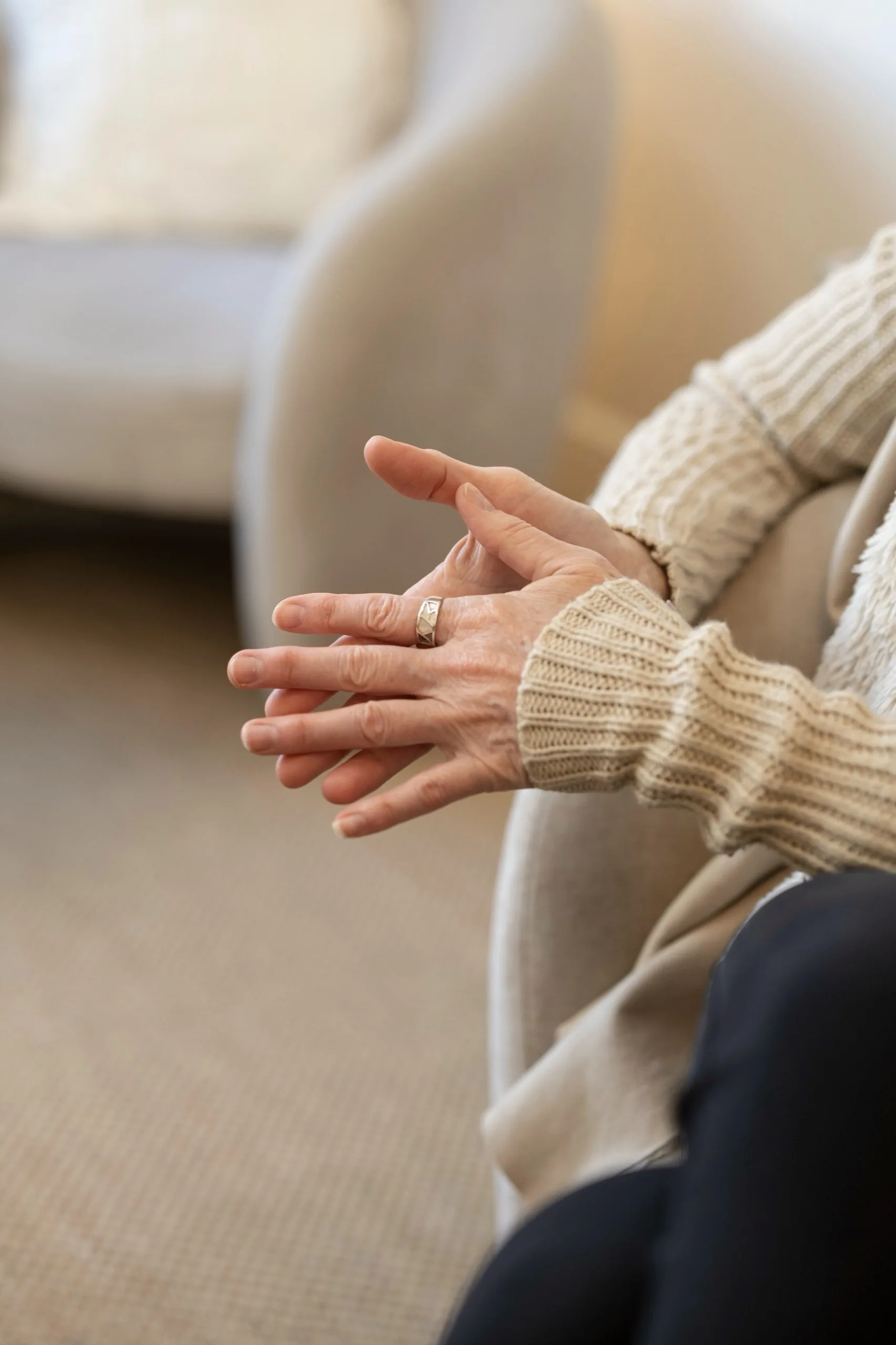 A client sitting in a therapy session, hands held open in front of them mid-conversation